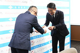 近藤常務理事が浅野市長に小切手を手渡す様子