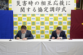 協定書に署名する浅野市長らの写真
