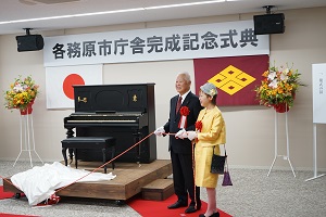 アンティークピアノ贈呈式でピアノの除幕をする井戸さんと宇野さんの写真