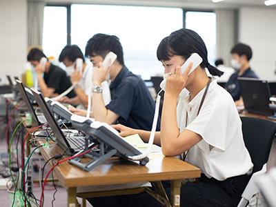 コールセンターで電話予約を受け付ける職員の写真