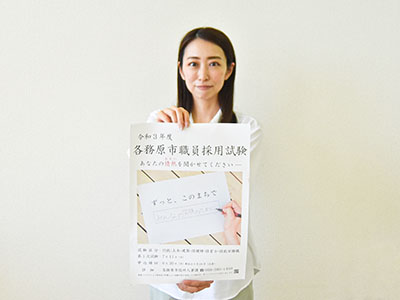職員採用試験のポスターを持つ担当職員の写真