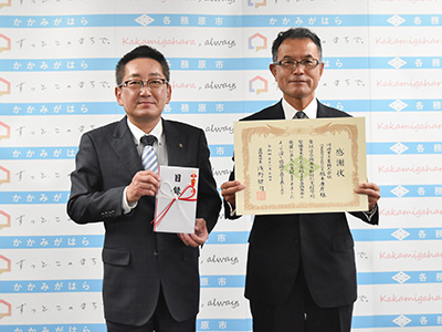 浅野市長と川崎重工の本川さんが目録と感謝状を持っている写真