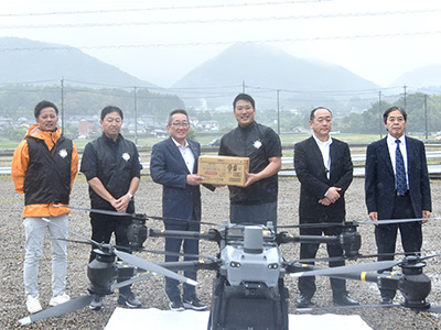 到着した物資を持ち記念撮影を受ける浅野市長と出席者