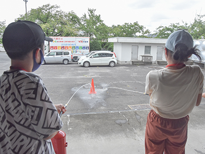消火器の取り扱いを体験する少年防火クラブ員の写真