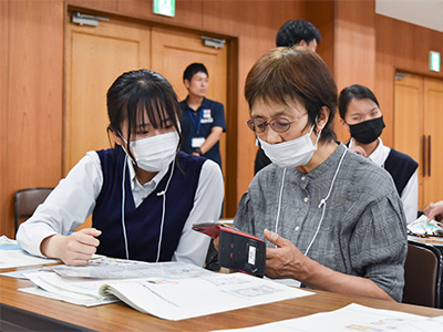 高齢者が各務野高生にスマホの使い方を教わっている写真