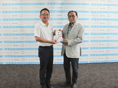 寄附目録を持ちながら記念撮影を受ける篠田さんと浅野市長の写真