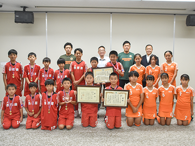 記念撮影に臨むしホッケースポーツ少年団と浅野市長と市ホッケー協会・横山会長の写真