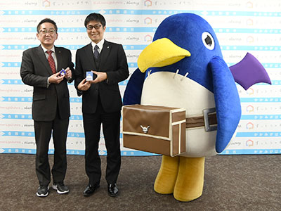 防犯ブザーを持つ浅野市長と猿橋社長の写真