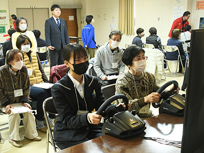 レーシングゲームを行う参加者と高校生