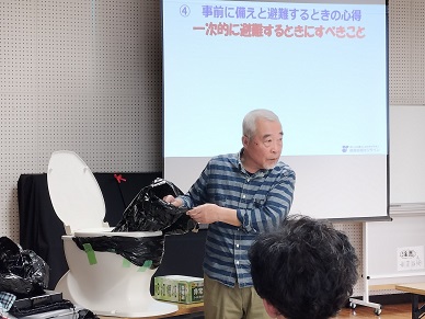 災害時のトイレの使い方を教える高木さん。「固形材が足りない場合、紙タイプの猫砂や新聞紙も役立つ。」