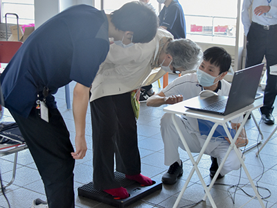 機器を使用する市民と、説明する病院スタッフ