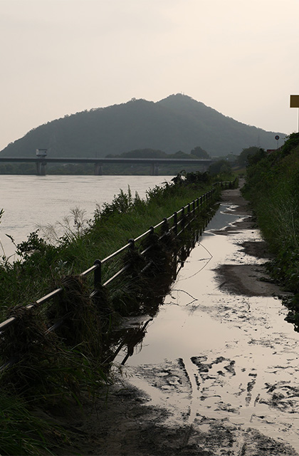 増水した木曽川と濁流に洗われた河畔遊歩道の写真
